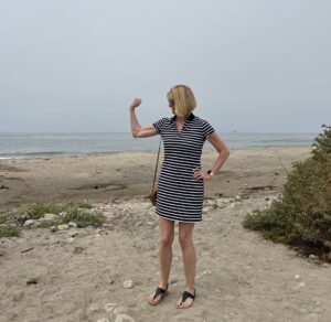 Andrea flexing her right bicep at the beach